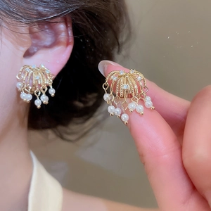 Close-up of 18k gold plated firework earrings with zircons and dangling pearls