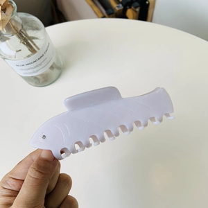 Macro view of light purple fish-shaped hair claw clip with unique bone-style teeth