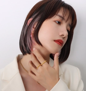 Gros plan d'une bague texturée plaquée or 18 carats et parure sur mannequin en blazer blanc