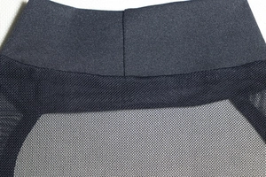Detail view of the black dress featuring mesh patchwork and fine stitching on the fabric