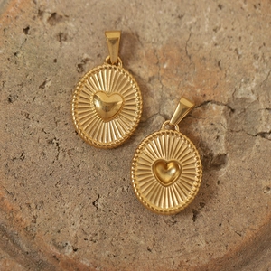 Detailed view of vintage gold-plated heart sunburst pendants on natural stone texture