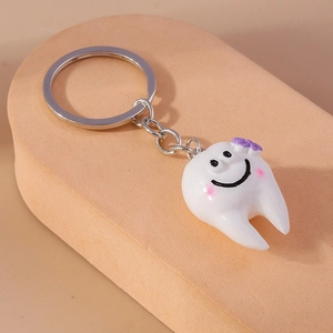 Dettaglio del simpatico portachiavi a forma di dente con sorriso e fiorellino viola