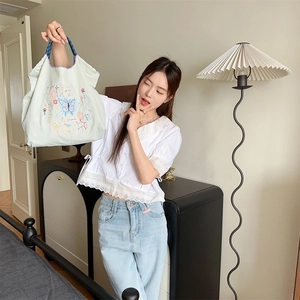 Gros plan sur le sac fourre-tout vert clair avec broderies de papillon bleu et étoiles