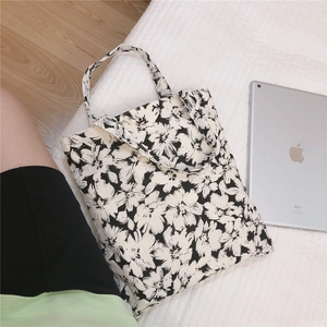 Detail of floral canvas tote bag next to an iPad showing the print and size on a white surface