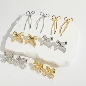 Detail view of gold and silver bow earrings with micro-set zircon and pearls on white stones