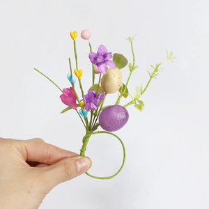Detail of Easter napkin ring with purple faux flowers, speckled eggs and green leaves
