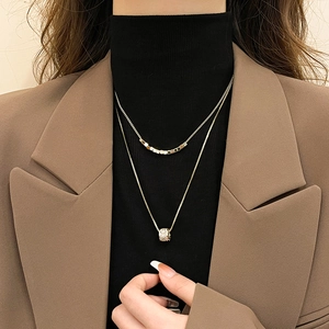 Detail of 18k gold plated double-layer necklace with square beads and cylinder pendant