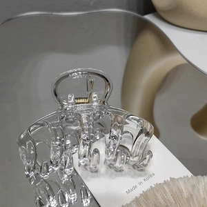 Detailed macro view of clear acrylic hair claw clip showing internal metal spring mechanism
