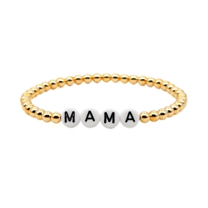 Detail of gold beaded bracelet with white letter beads spelling MAMA in a minimalist style