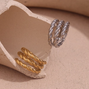 Artistic close-up of gold and silver twisted spiral rings on a textured ceramic surface