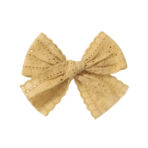 Detail of yellow lace bow hair clip featuring intricate Broderie Anglaise embroidery texture