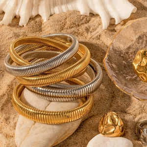 Chic gold and silver Tubogas steel bangles with chunky rings on a beach sand setting