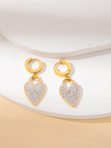 Golden heart drop earrings with shimmering silver rhinestones on a stone pedestal