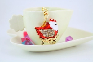 Detail of red enamel hen keychain with sparkling rhinestones on golden metal base