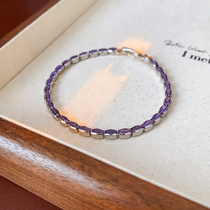 Macro shot of a minimalist silver bracelet featuring oval purple zircon stones