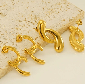 Macro detail of irregular geometric 18k gold plated earrings on a beige stone base