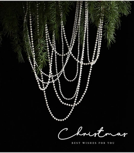 Detail of white pearl bead chain hanging on green pine branches for Christmas decor