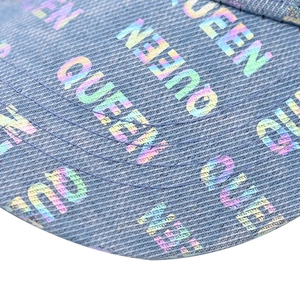 Dettaglio macro della visiera in denim con motivi QUEEN a stampa laser iridescente