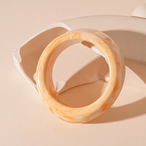 Detail of marbled acrylic resin bangle with orange and white patterns on art stand