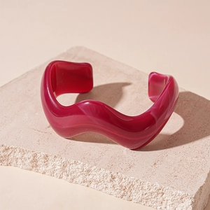 Detail view of burgundy wavy resin bangle with marble texture on stone display