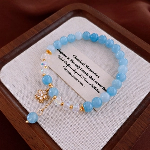 Détail d'un bracelet de perles bleues avec un pendentif fleur doré orné de zircons