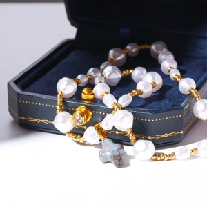Macro d'un collier de perles baroques avec pendentif croix dans un écrin en velours bleu foncé