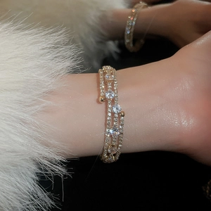 Macro detail of multilayer gold zircon bracelet with sparkling diamonds on female wrist