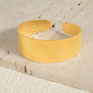 Detail of 18k gold plated stainless steel cuff bracelet with hammered texture finish