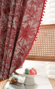 Detail of red tropical floral jacquard curtain with elegant crimson pom-pom fringe trim