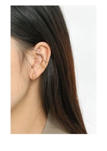 Detail of three-piece gold earring set featuring rope and bead textures on a model