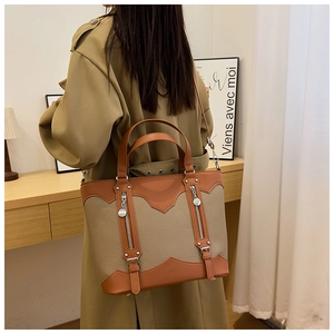 Detail view of the brown patchwork leather tote bag with silver zippers and buckles