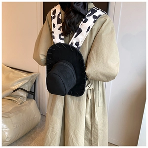 Detail of creative cowboy hat backpack featuring stylish cow print straps in black suede