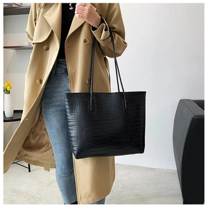 Detail of black crocodile texture tote bag worn on shoulder for stylish workwear look