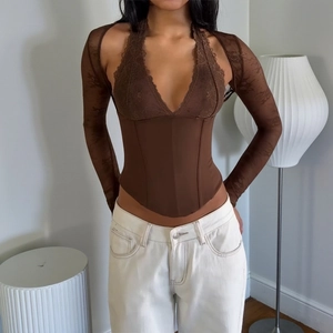 Close-up of deep brown lace corset top with sheer mesh sleeves and halter neck design
