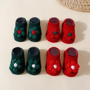 Detail of red and green knit baby socks with 3D floral accents and non-slip soles