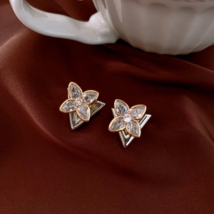 Detailed close-up of a zircon flower stud earring with silver and gold finish detailing