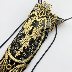 Close-up of gothic black lace arm chain with intricate gold embroidery and baroque patterns