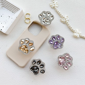 Luxury rhinestone cat paw phone grip stands in multiple colors on a textured background