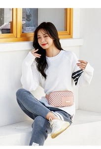Detailed close-up of a pink checkered waist bag with gold metal plaque and adjustable strap
