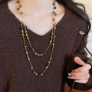 Detail of layered Tiger Eye stone and champagne crystal necklace on brown sweater