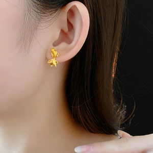 Gros plan d'une boucle d'oreille carpe koi dorée portée par un mannequin sur fond sombre
