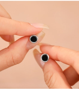 Close-up of minimalist S925 sterling silver stud earrings with black onyx held by hand