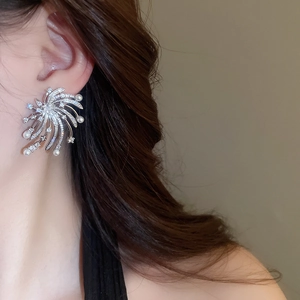 Close-up of elegant firework star earrings with pearls and zircons worn by a model