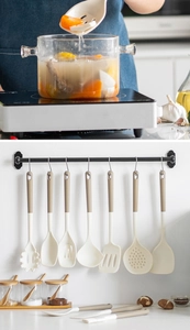 Close-up of cream silicone cooking utensils set with wooden handles in a kitchen setting