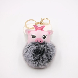Close-up of pink pig cartoon head with grey faux fur pompom and golden metal keychain