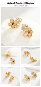 Close-up of gold-plated flower stud earrings with cream enamel petals and zircon