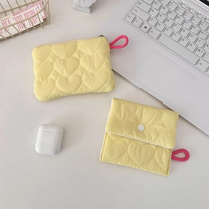 Close-up of heart-quilted yellow pouches for sanitary pads and small gadgets with pink lanyard