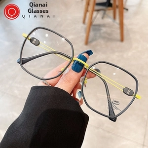 Dettaglio degli occhiali poligonali neri oversize con aste gialle vivaci