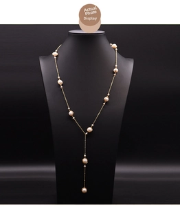 Detail of a golden Y-shaped long necklace with white pearls on a black neck model