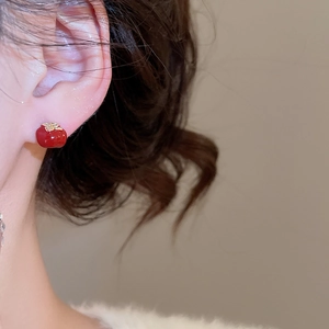 Close-up of red persimmon stud earring with gold leaf detail worn by a model